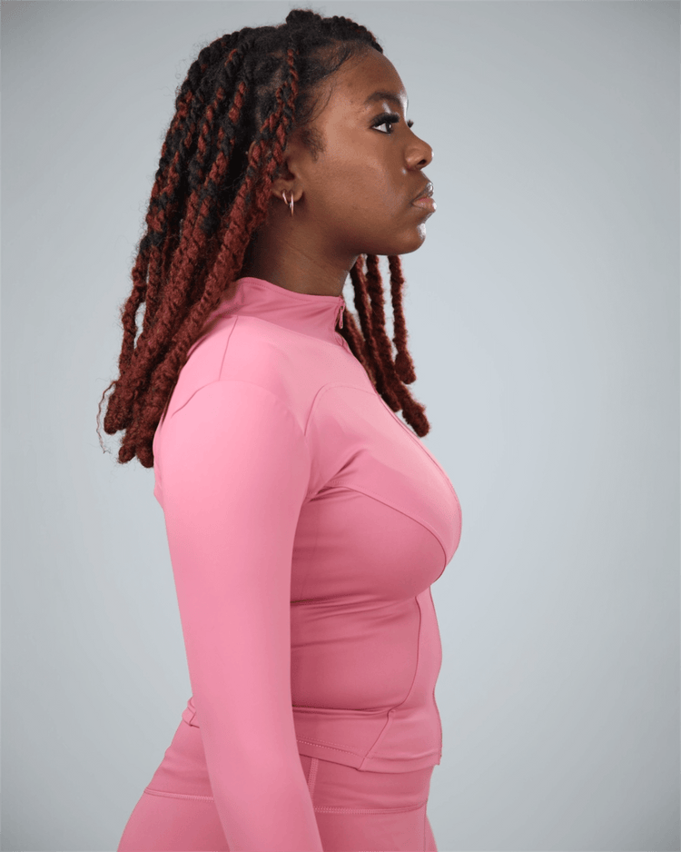 Woman wearing a pink long-sleeve top against a gray background
