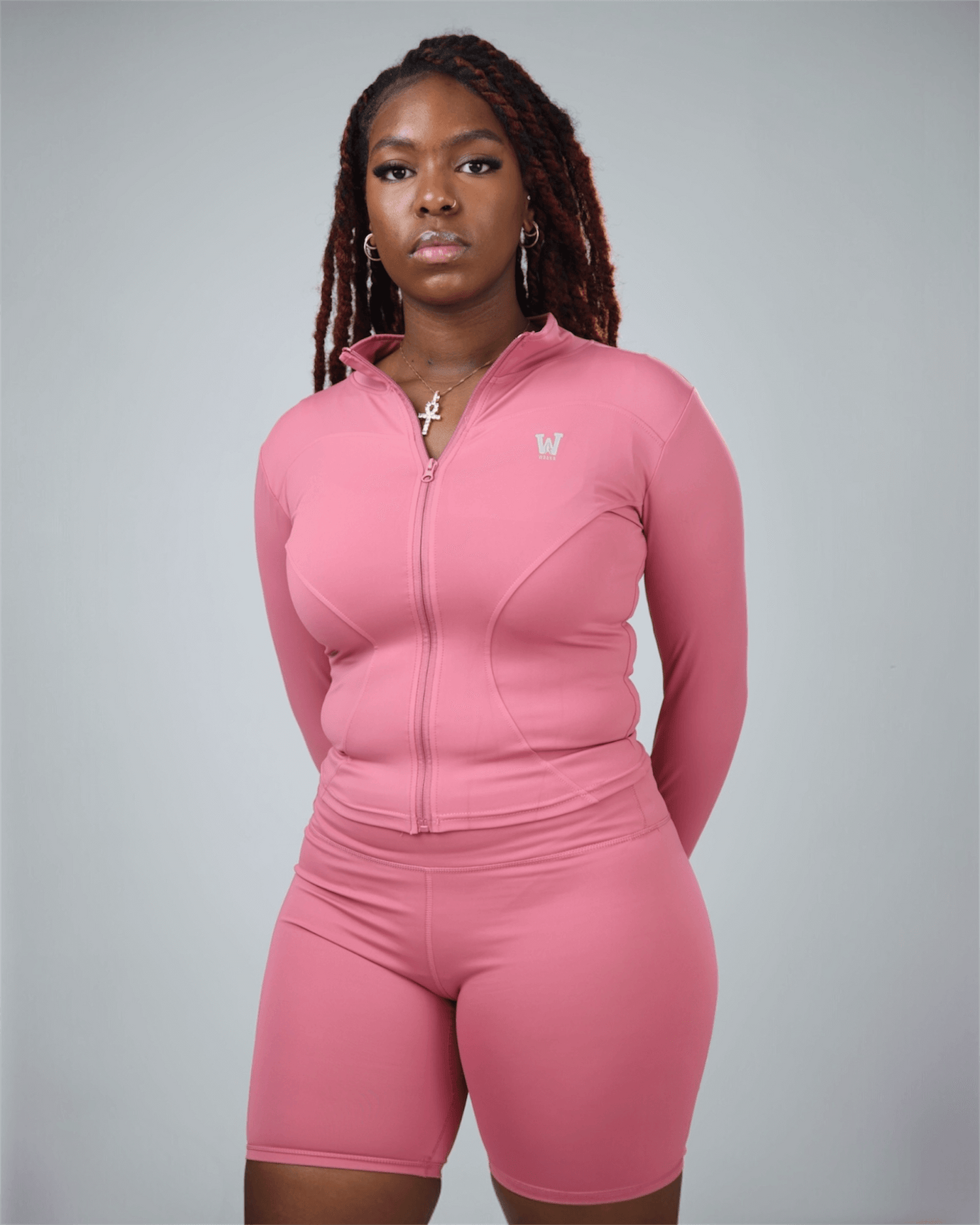 Person wearing a pink athletic outfit with a logo on a gray background