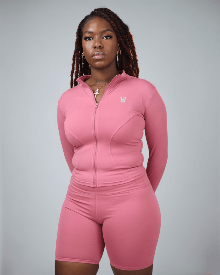 Person wearing a pink athletic outfit with a logo on a gray background