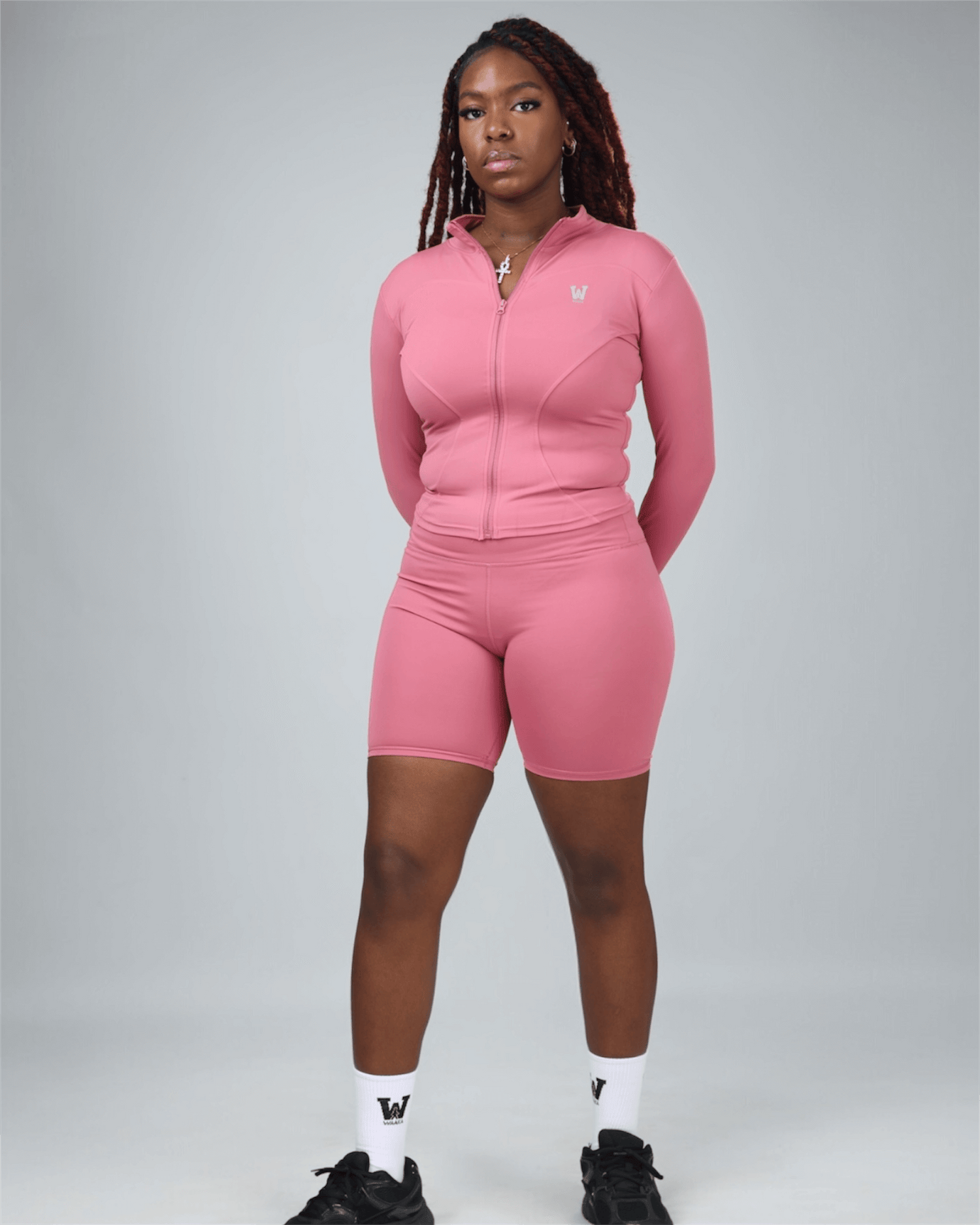Person wearing a pink tracksuit on a gray background