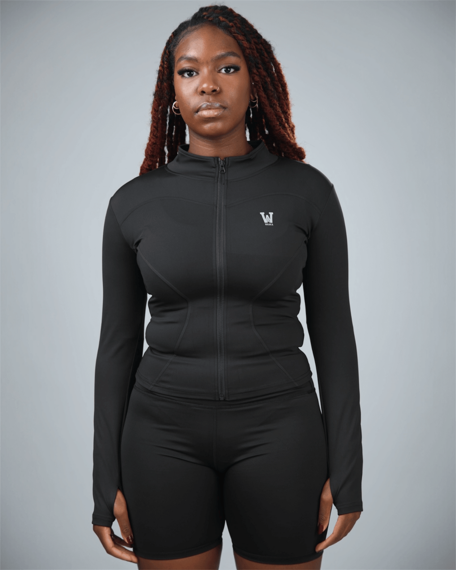 Person wearing a black athletic outfit with a logo on a gray background