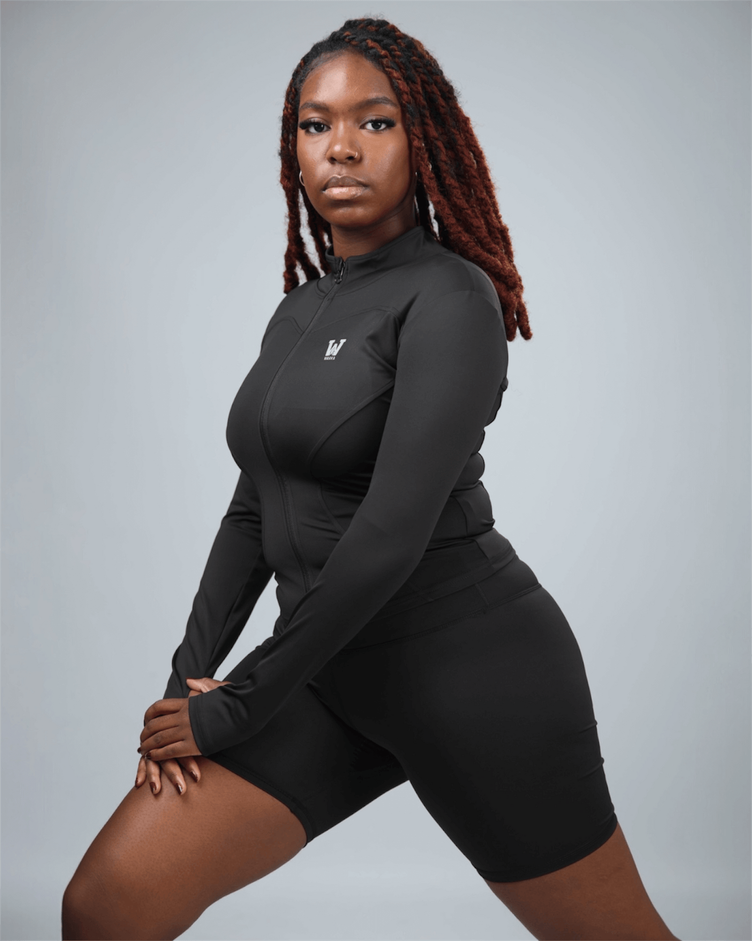 Person wearing a black athletic outfit with a logo on a gray background