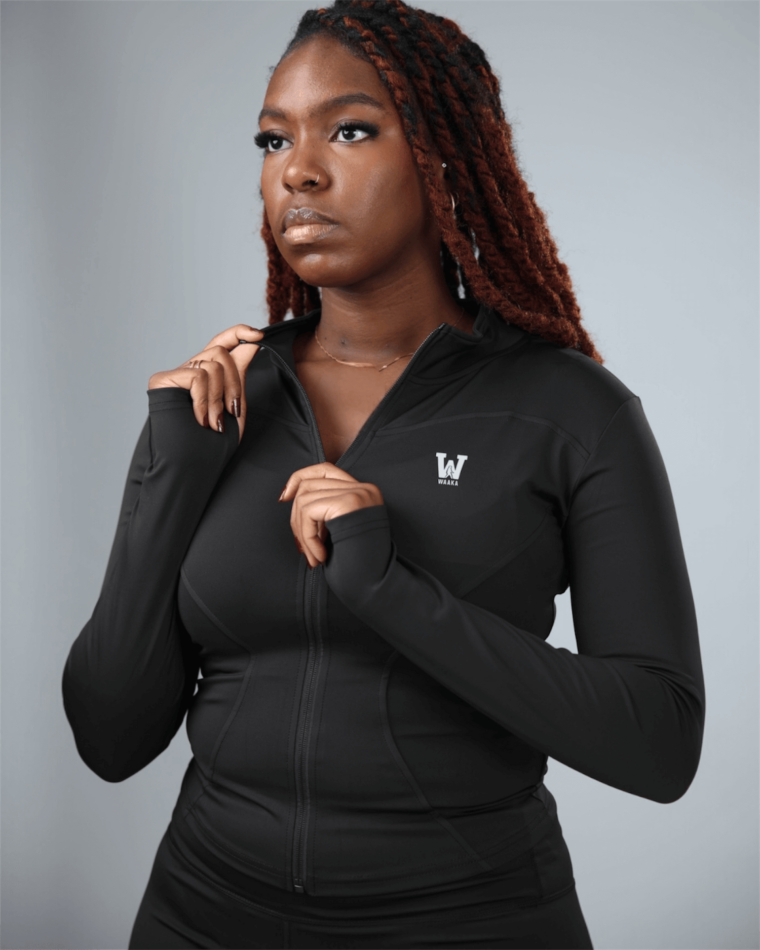 Woman wearing a black hoodie with a logo on a gray background