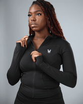 Woman wearing a black hoodie with a logo on a gray background