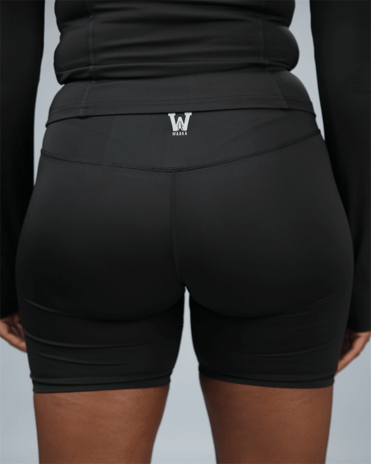 Black athletic shorts with a logo on the back pocket against a neutral background