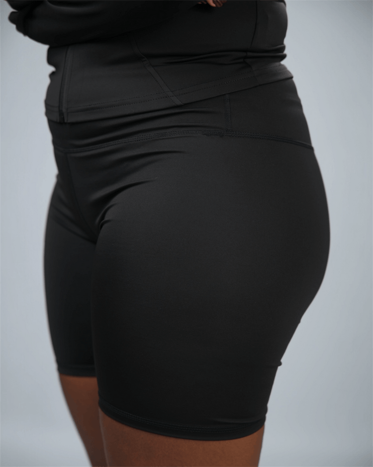 Black athletic shorts worn by a person on a gray background