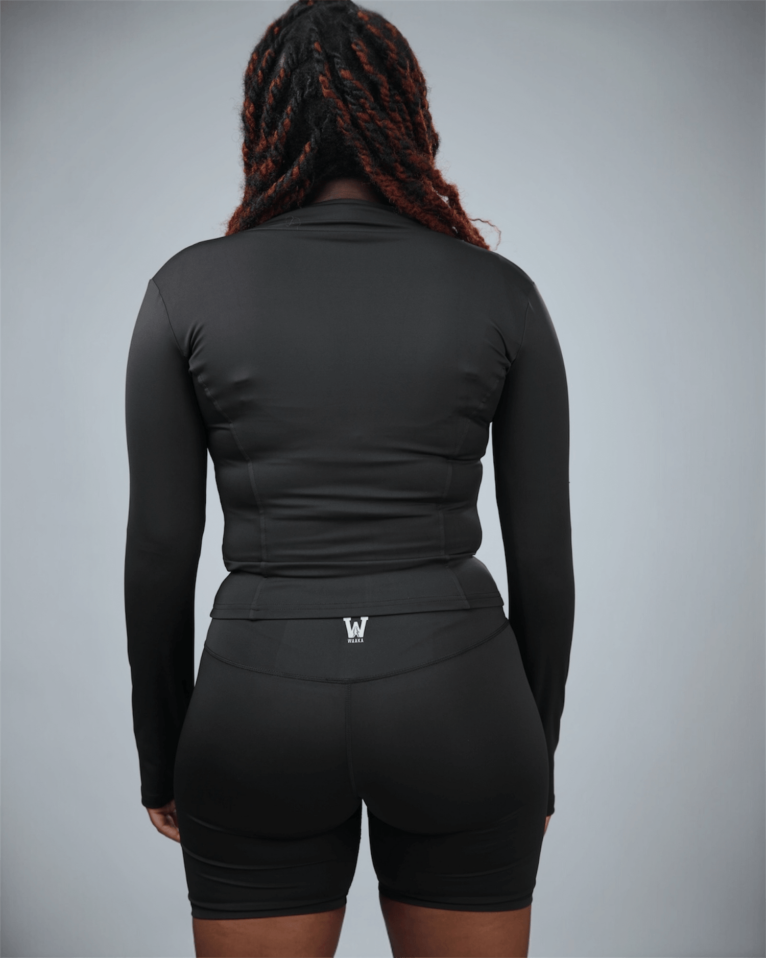 Person wearing a black athletic outfit with a logo on a gray background