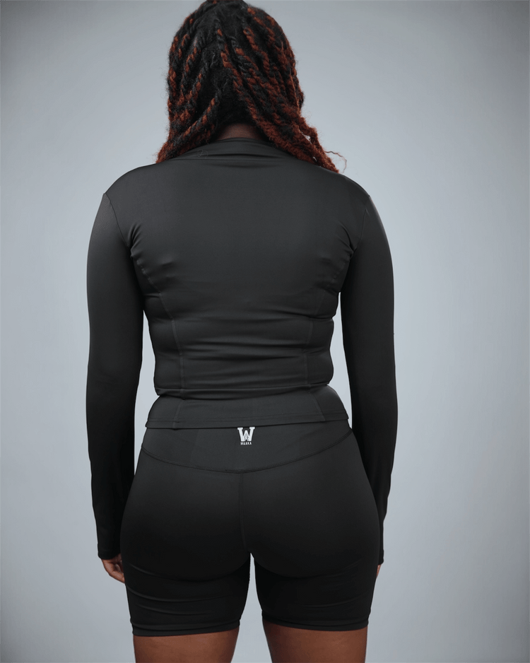 Person wearing a black athletic outfit with a logo on a gray background