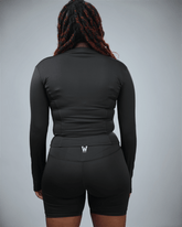 Person wearing a black athletic outfit with a logo on a gray background